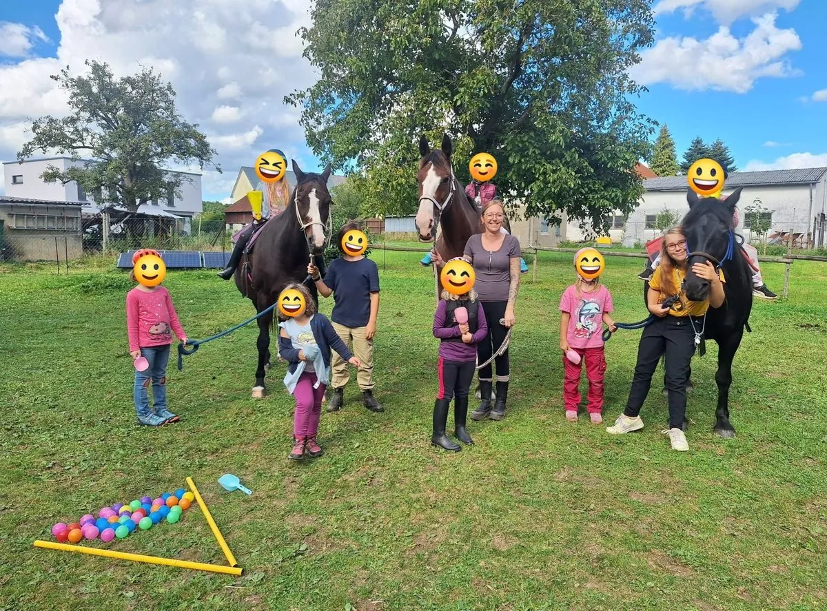 Kindergruppe mit Pferden auf der Wiese